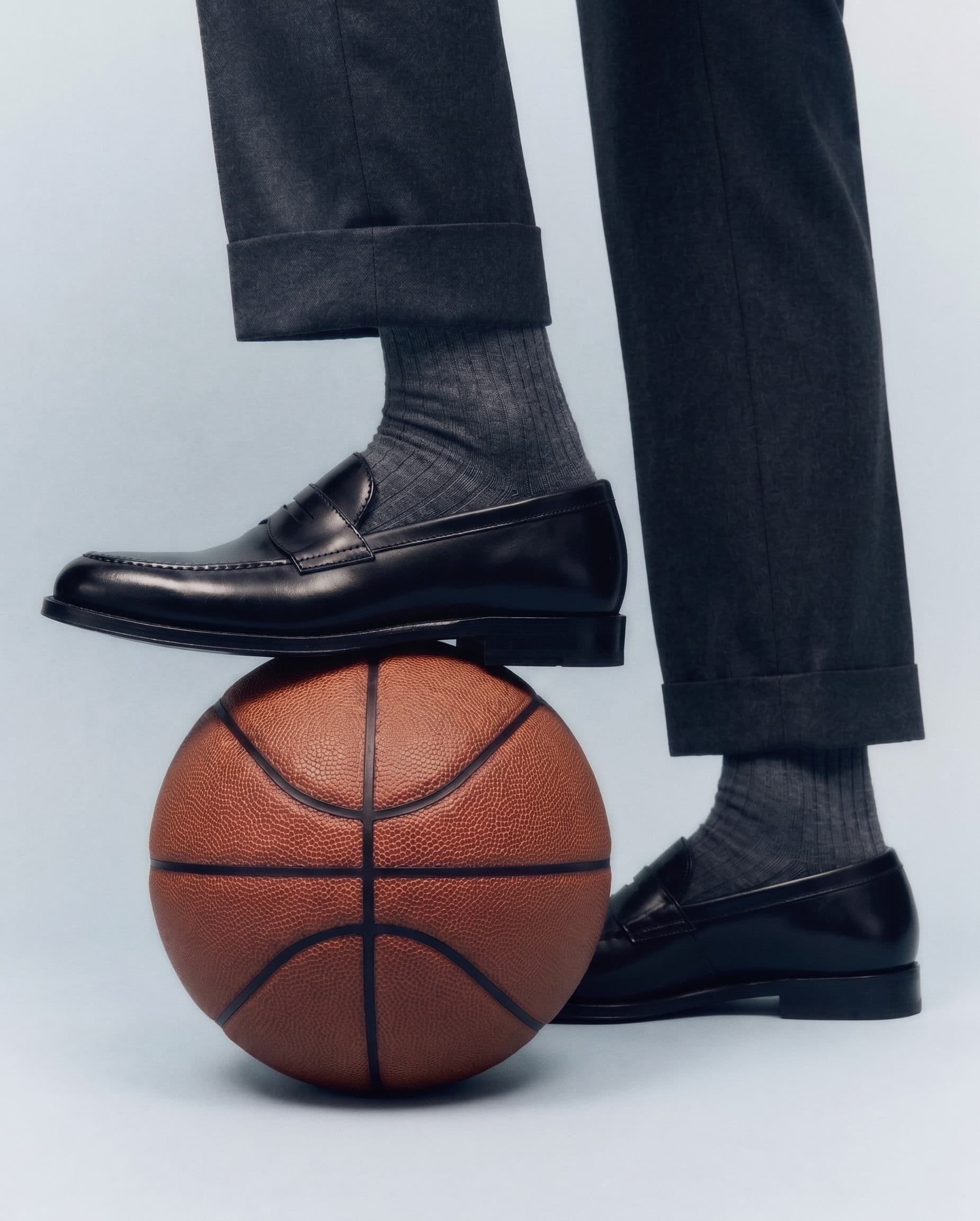 A black leather brogue and tailored trouser resting on a basketball