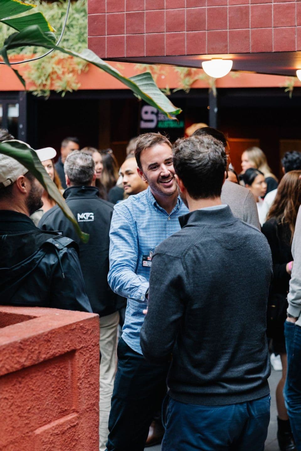 Two guests shaking hands in the courtyard at a Notice Happy Hour