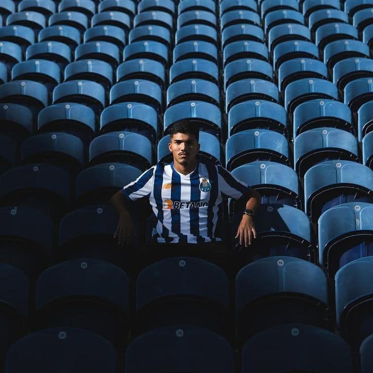 A footballer in blue and white stripes sitting alone in an empty stand